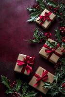 Gifts wrapped in brown paper with red ribbons and holiday decorations on dark background photo