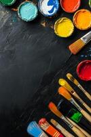 Colorful arrangement of paintbrushes and paint containers on a black surface for creative projects photo