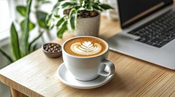 Warm coffee cup with latte art on a cozy knitted blanket beside a laptop photo