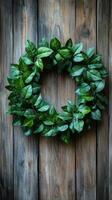 Decorative green wreath made of fresh leaves and berries on wooden background photo