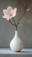 Elegant pink flower in a simple white vase against a soft gray background photo