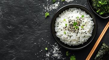 Delicious white rice served in a bowl with chopsticks and fresh herbs on a dark background photo