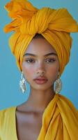 Woman wearing a yellow turban and wooden earrings with a soft expression against a dark background photo