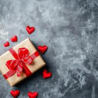 Gift wrapped in beige paper with red ribbon and hearts on dark textured background photo
