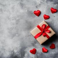 Gift wrapped in beige paper with red ribbon and hearts on dark textured background photo