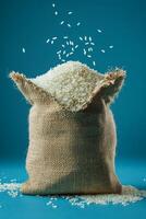 Sack of white rice with grains pouring out against a blue background photo