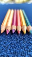 Colorful pencils arranged in a vibrant pattern on a glittery blue surface photo