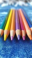 Colorful pencils arranged in a vibrant pattern on a glittery blue surface photo