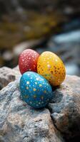 Colorful decorative eggs resting on pebbles in a natural setting during springtime photo
