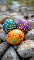 Colorful decorative eggs resting on pebbles in a natural setting during springtime photo