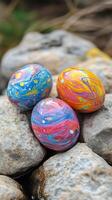 Colorful decorative eggs resting on pebbles in a natural setting during springtime photo