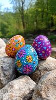 Colorful decorative eggs resting on pebbles in a natural setting during springtime photo