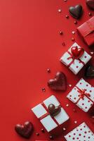Gift boxes and chocolates arranged on a vibrant red background for a festive celebration photo
