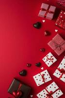 Gift boxes and chocolates arranged on a vibrant red background for a festive celebration photo