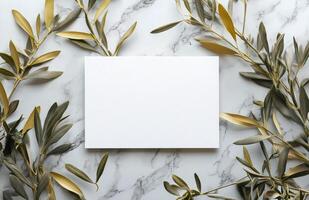 Blank card surrounded by olive branches on marble surface in natural light photo