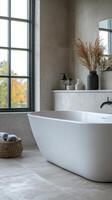 Elegant freestanding bathtub in bright bathroom with large windows and natural decor photo