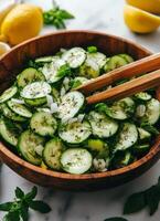 Fresh cucumber salad with herbs and onions in a wooden bowl on a kitchen countertop photo