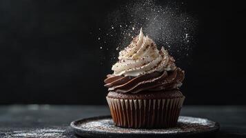 Decadent chocolate cupcake with frosting and cocoa powder dusting in dimly lit kitchen photo