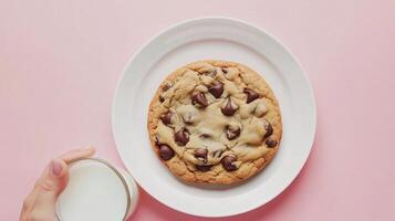 Delicious chocolate chip cookie served with a glass of milk on a soft pink background photo