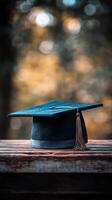 Graduation cap on wooden table with blurred background showcasing autumn colors photo