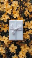 Gift wrapped in white resting on a bed of vibrant yellow flowers during daylight photo