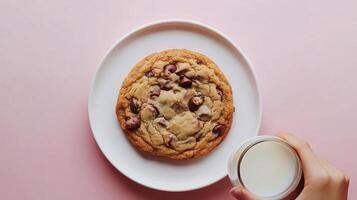 Delicious chocolate chip cookie served with a glass of milk on a soft pink background photo