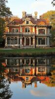 Historic mansion reflecting in calm waters surrounded by trees in autumn photo