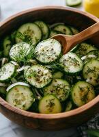 Fresh cucumber salad with herbs and onions in a wooden bowl on a kitchen countertop photo