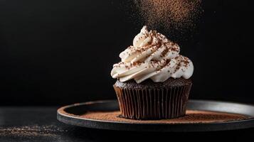 Decadent chocolate cupcake with frosting and cocoa powder dusting in dimly lit kitchen photo