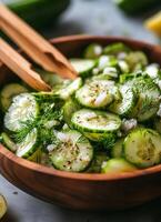 Fresh cucumber salad with herbs and onions in a wooden bowl on a kitchen countertop photo