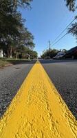 Yellow line on a quiet street captured under clear blue sky during daytime hours photo