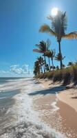 Waves crashing on sandy beach with palm trees and clear blue sky in the background photo