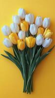 Colorful bouquet of white and yellow tulips arranged on a bright yellow background photo