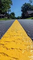 Yellow line on a quiet street captured under clear blue sky during daytime hours photo