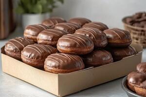 Assorted chocolate glazed donuts arranged in a neat box on a marble countertop photo