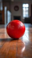 Red bowling ball rolls down a vintage wooden lane in a spacious bowling alley photo