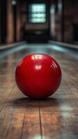 Red bowling ball rolls down a vintage wooden lane in a spacious bowling alley photo