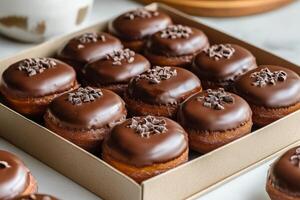 Assorted chocolate glazed donuts arranged in a neat box on a marble countertop photo
