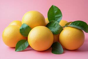 Fresh yellow grapefruit with green leaves arranged on pink background for vibrant display and marketing photo
