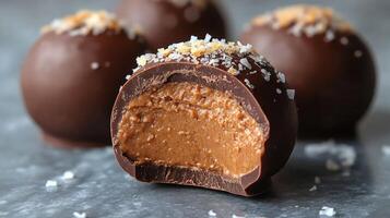 Delicious chocolate truffles with creamy filling and sea salt topping on a gray surface photo