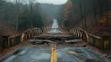 Abandoned road with collapsed bridge surrounded by autumn foliage on a rainy day photo
