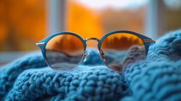 Brown tortoiseshell sunglasses resting on a cozy knitted sweater in a winter setting at sunset photo