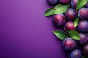 Fresh plums with leaves arranged on a vibrant purple surface photo