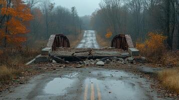 Abandoned road with collapsed bridge surrounded by autumn foliage on a rainy day photo