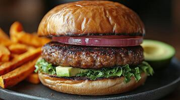 Delicious burger with avocado and sweet potato fries on a rustic table photo