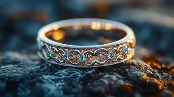 Intricate silver ring with floral motifs displayed on a textured stone surface photo