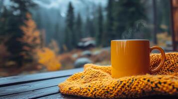 Warm tea in a glass mug resting on a cozy blanket by a log cabin in autumn woods photo