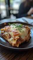 Homemade lasagna served on a dark plate with melted cheese and herbs atop, enjoyed during lunch photo