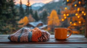 Warm tea in a glass mug resting on a cozy blanket by a log cabin in autumn woods photo
