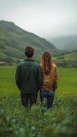 Couple enjoying a peaceful moment in lush green fields with mountains in the background photo